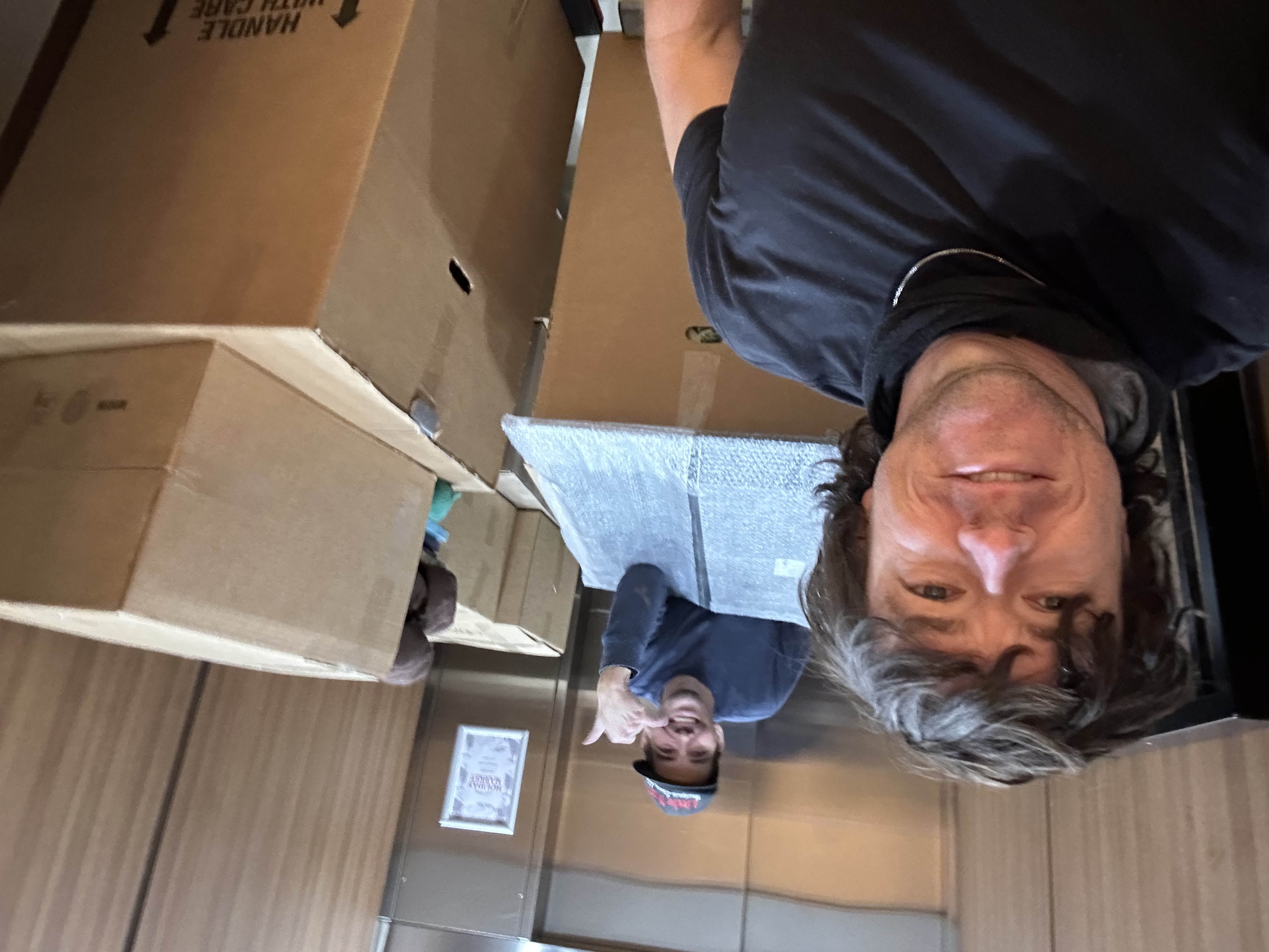 Liberty Movers crew smiling in an elevator with moving boxes during an apartment move in Huntington WV — friendly, professional movers