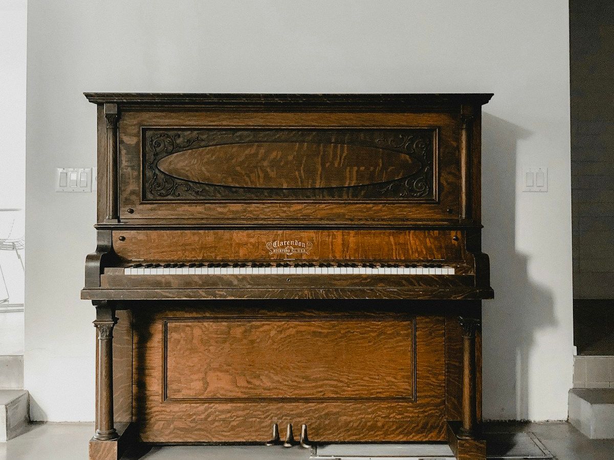 Upright piano against a white wall, ready to be moved by Liberty Movers